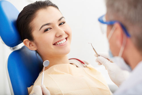 Patient sitting in dental chair smiling and doctor holding dental tools at Peak Endodontics in Covington, WA